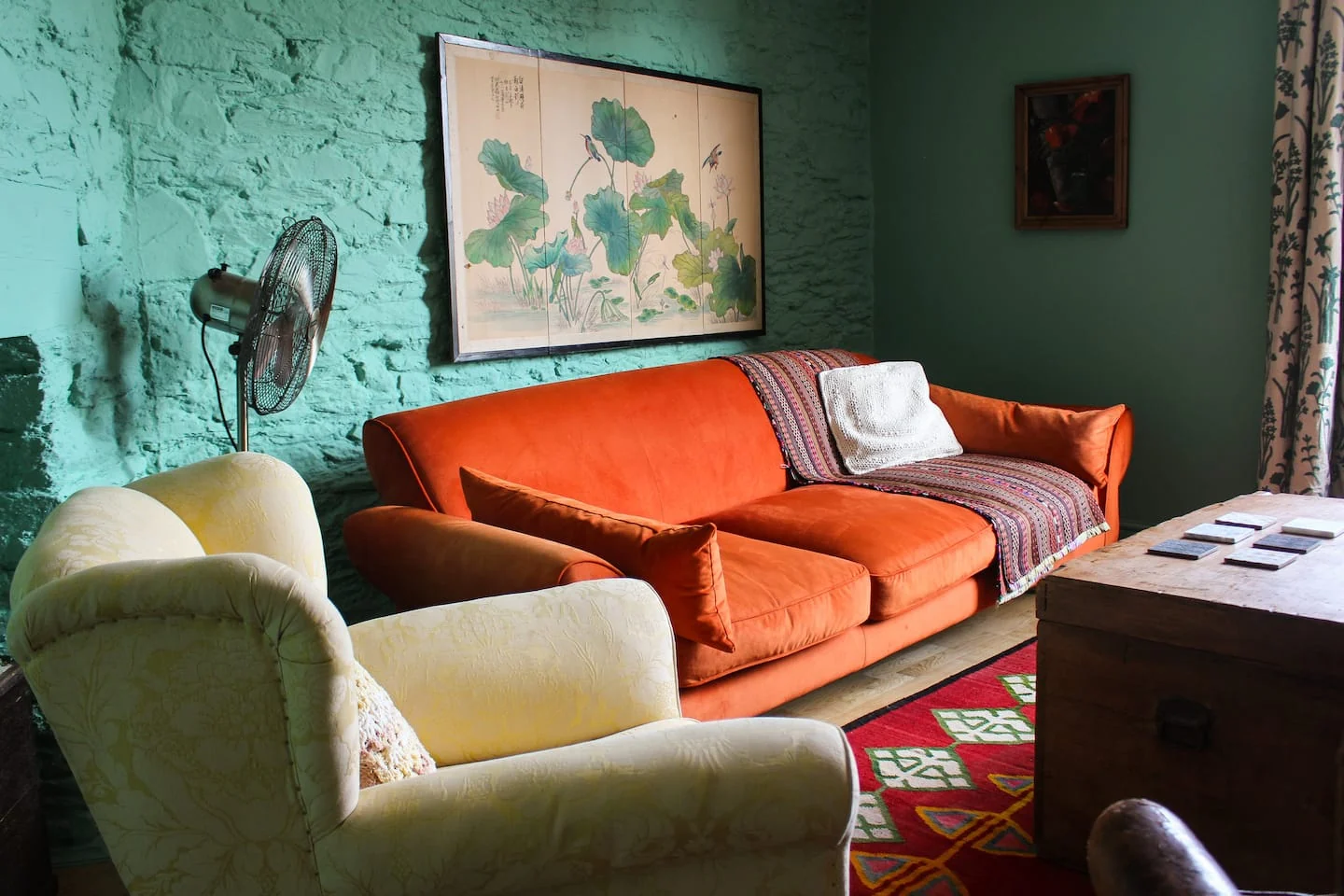 Orange velvet sofa against a textured green wall