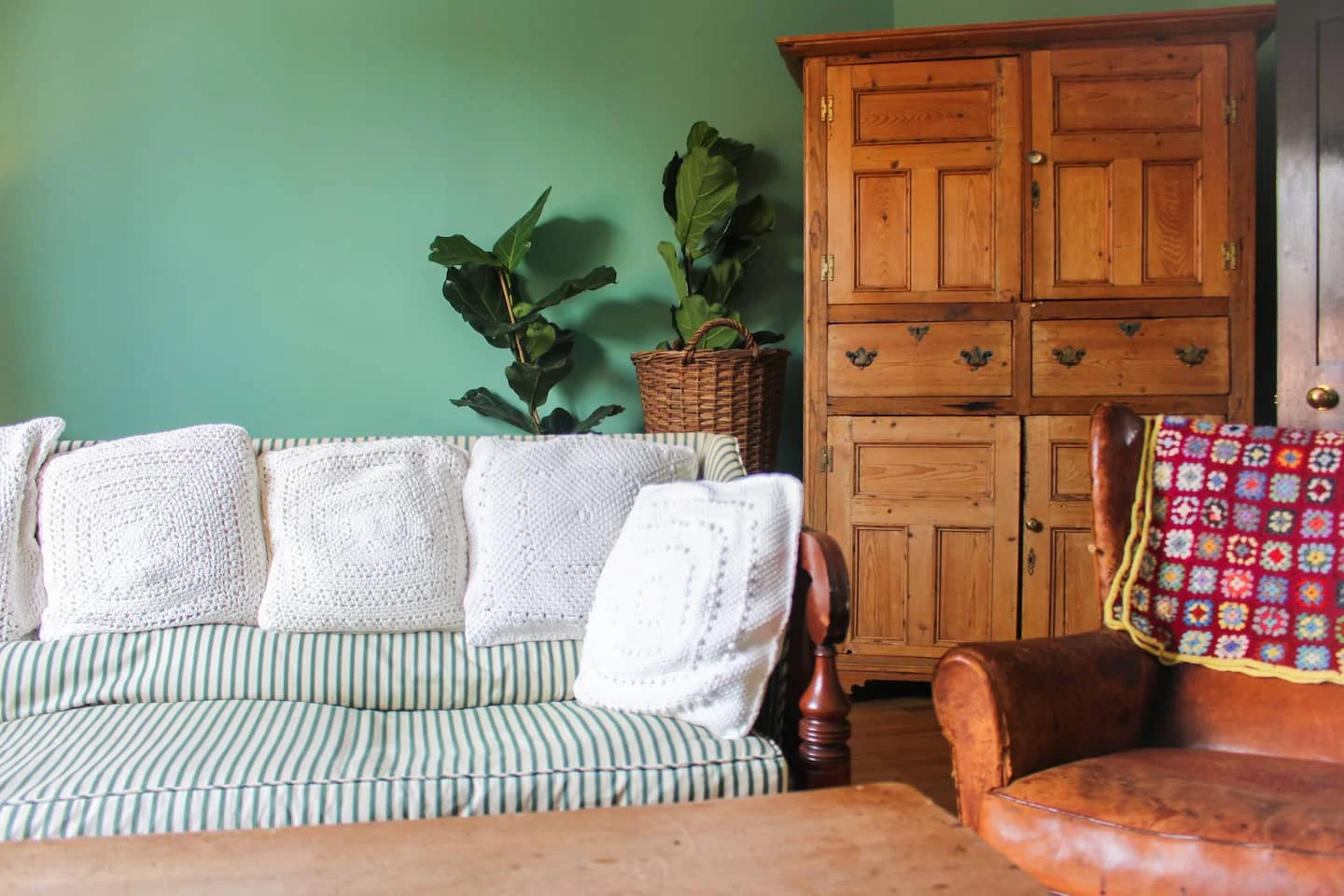 Striped sofa and vintage wooden cupboard against green walls