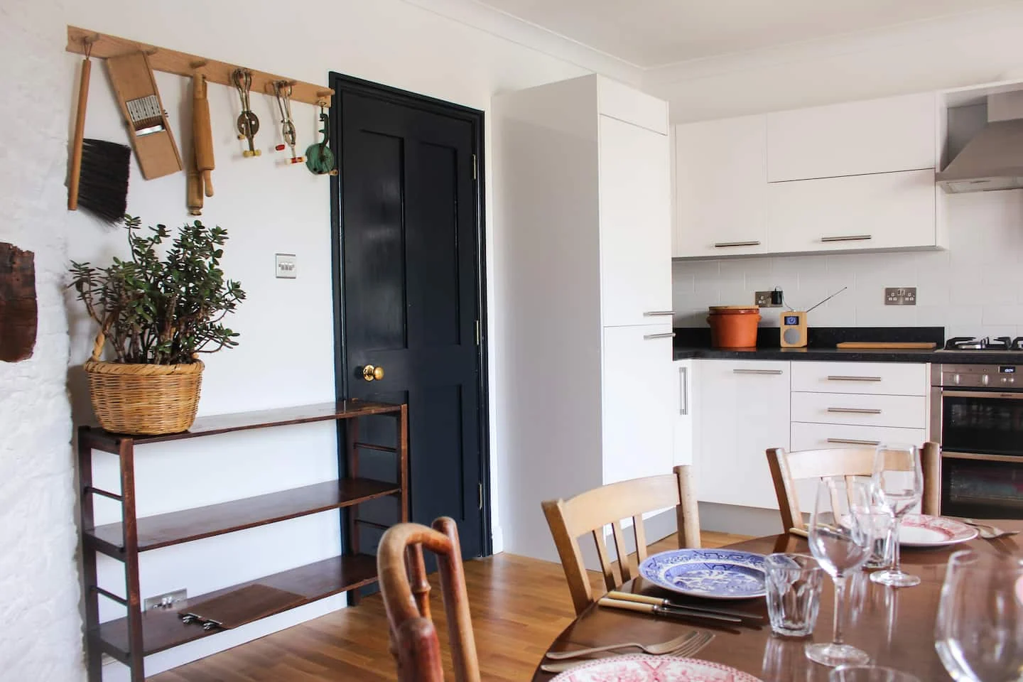 Dining table beside a white kitchen and dark door