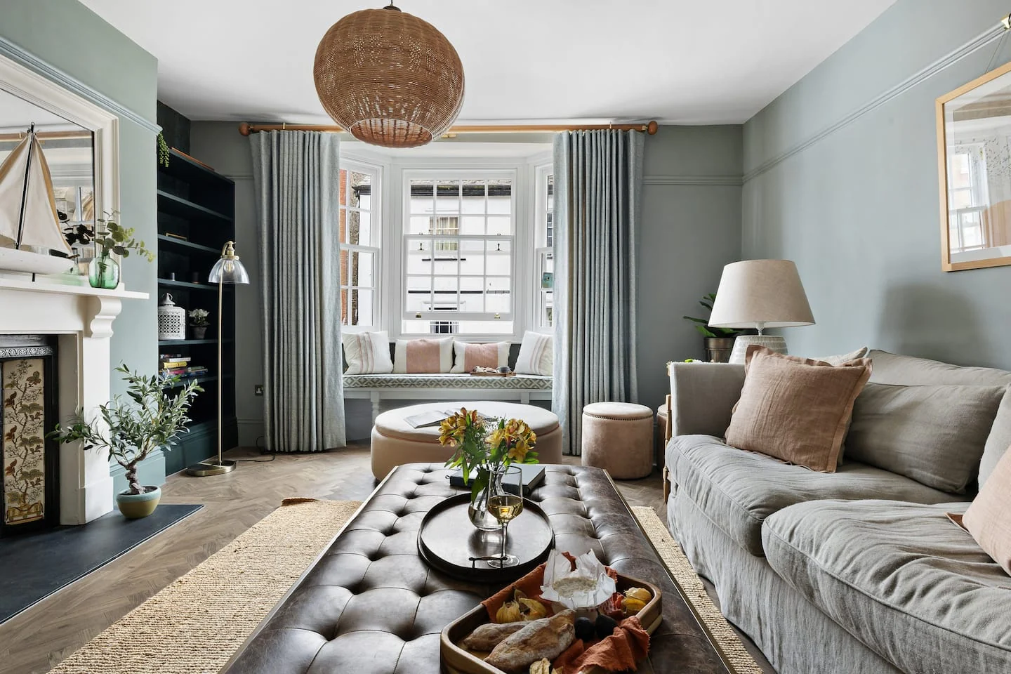 Pale green sitting room with a sofa, fireplace and bay window