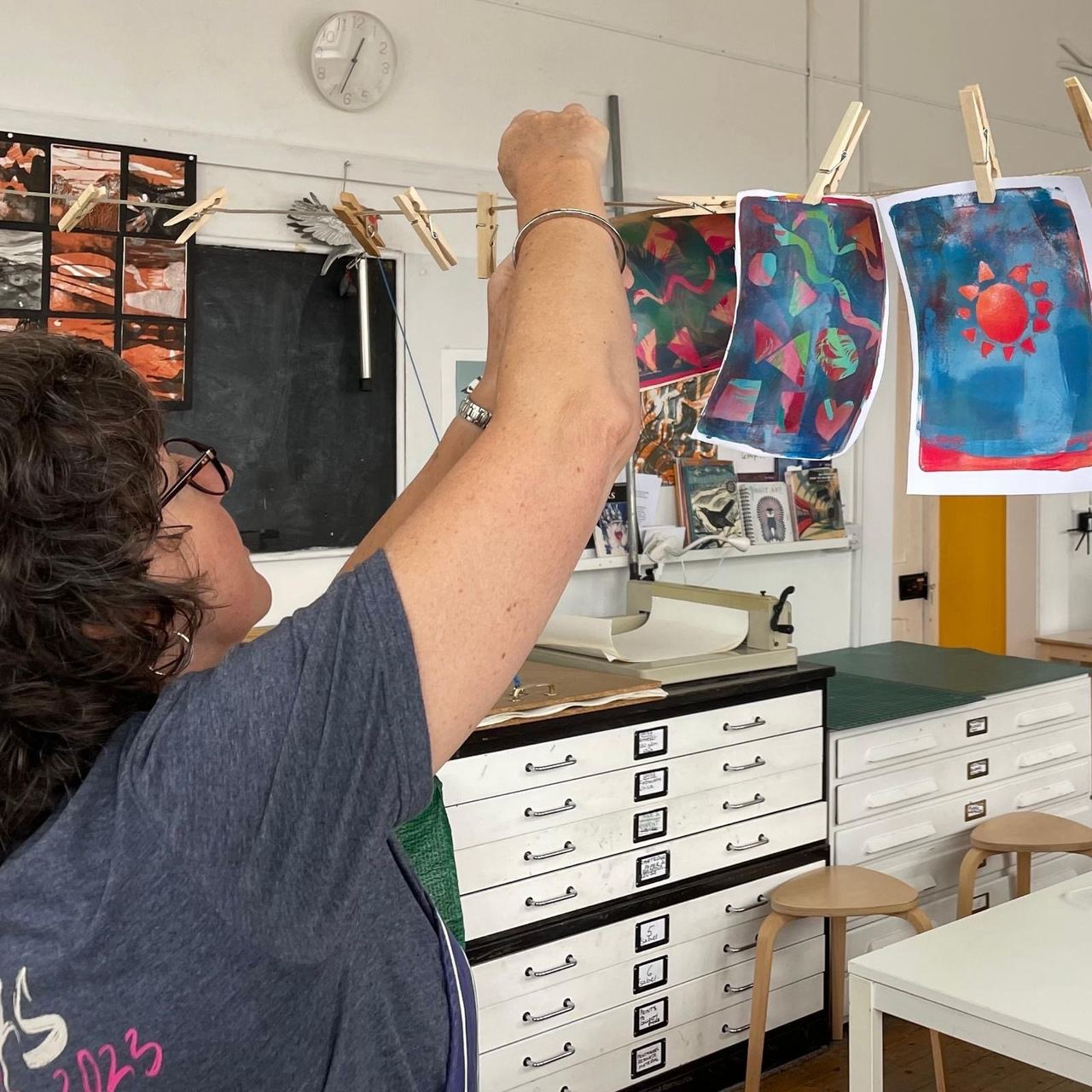 A participant hanging colourful prints to dry in the Art House studio