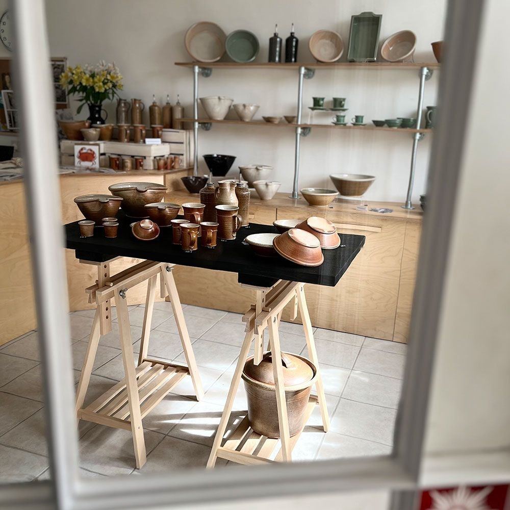 Handmade ceramics displayed on shelves and a central table in Arwyn Jones’s shop