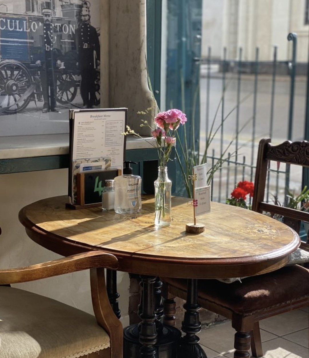 A round café table by the window with flowers