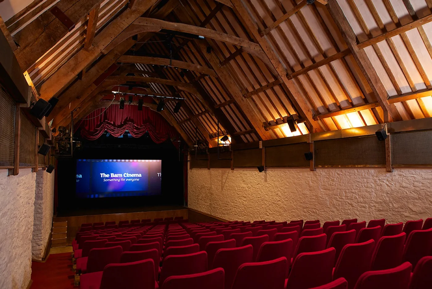 Red cinema seats below the timber roof of Dartington’s Barn Cinema