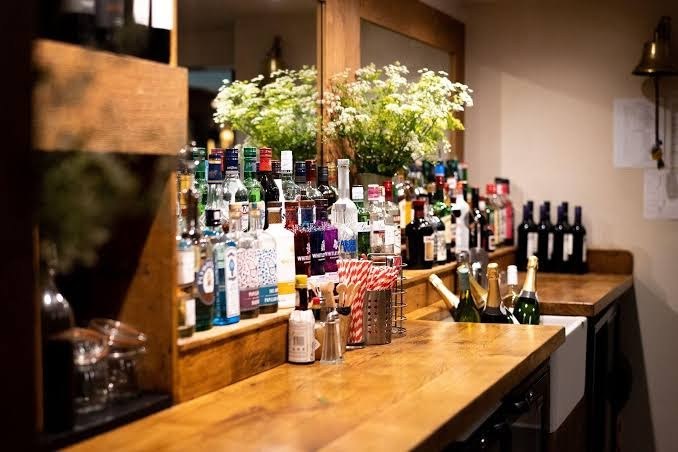 Wooden bar with bottles, flowers and wine at Bickley Mill Inn