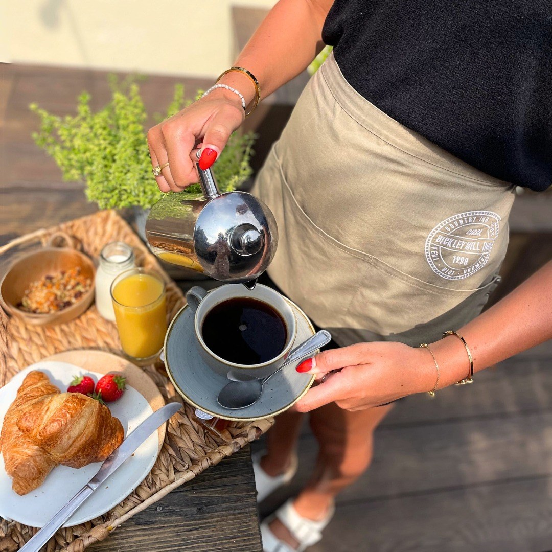 Coffee being poured beside a croissant and fruit at Bickley Mill Inn