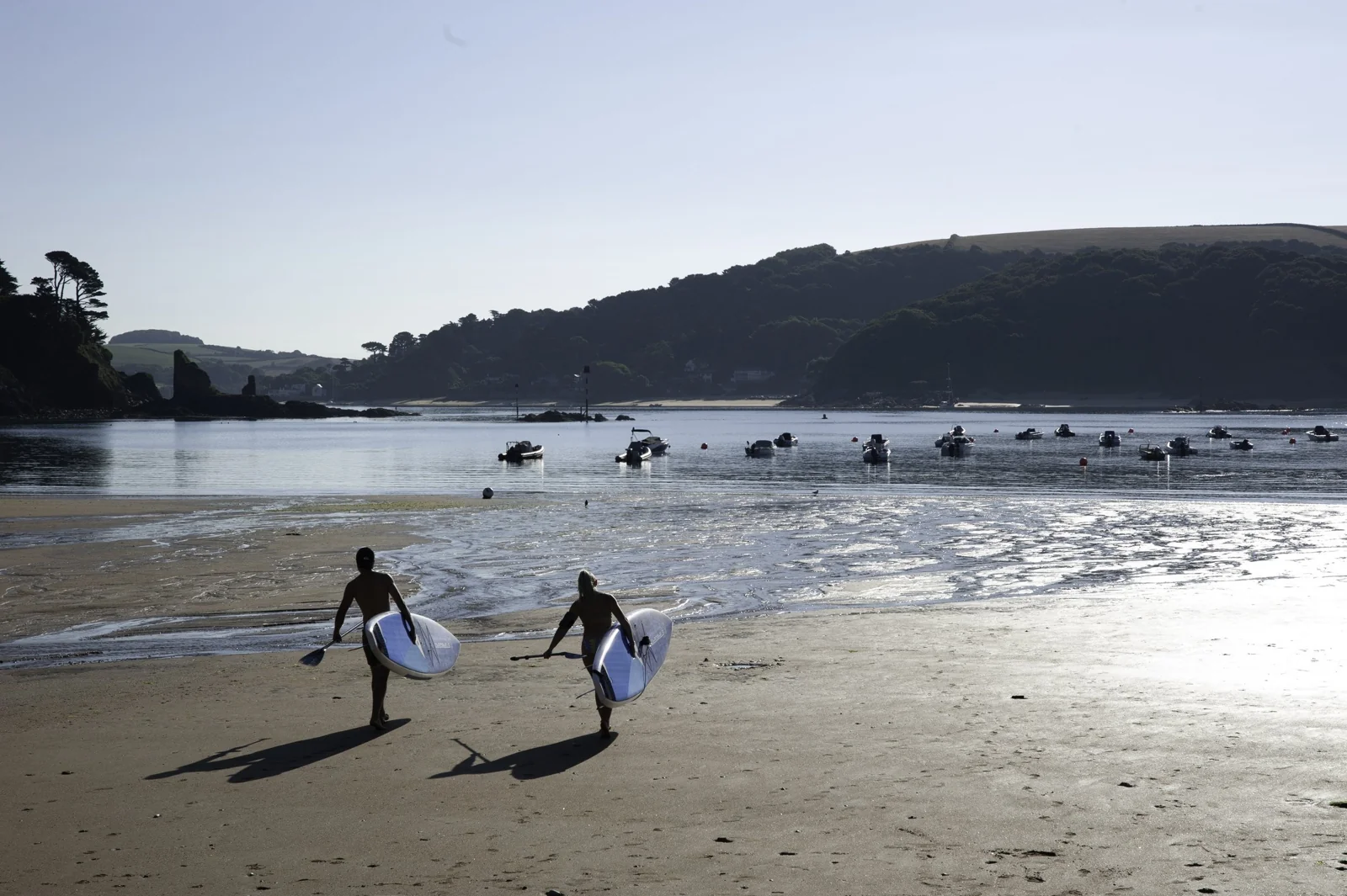 Paddleboarders walking across South Sands