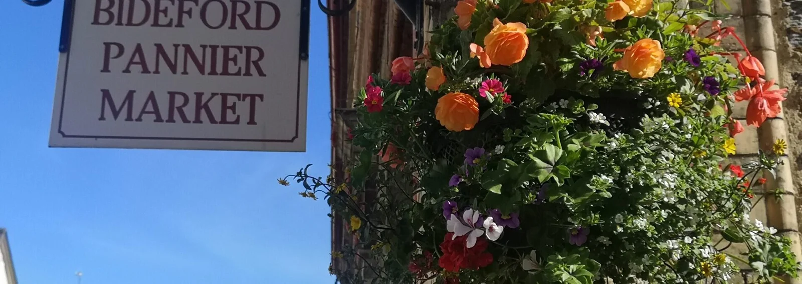 Bideford Pannier Market sign beside a flowering hanging basket