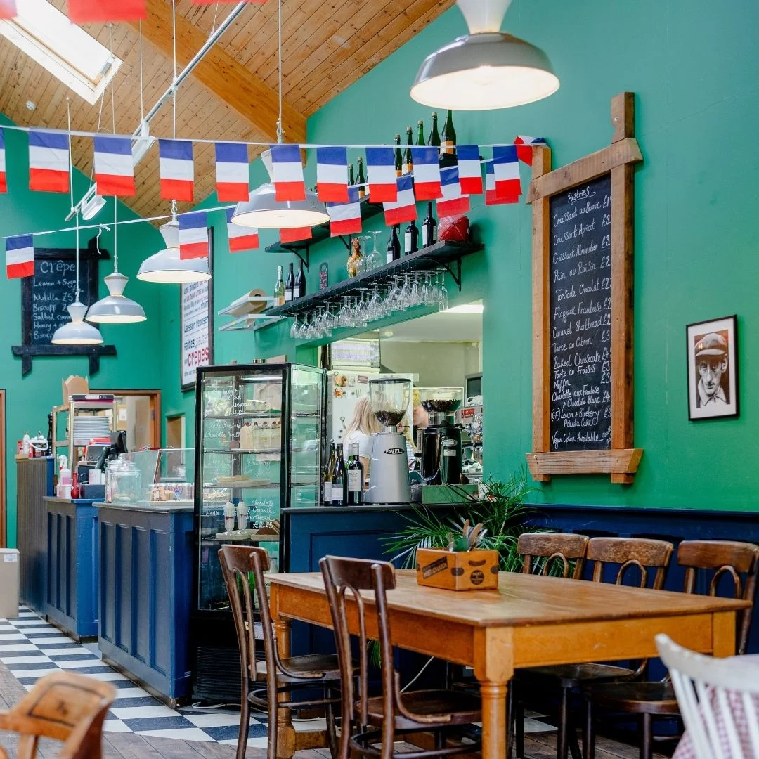 French bunting above wooden tables in the green-walled Café du Parc