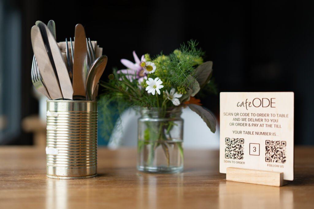 Flowers and a menu on a wooden table at cafe ODE
