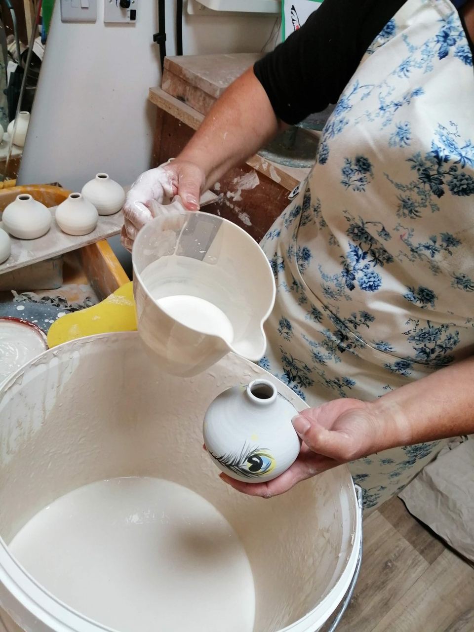 A potter decorating a freshly made ceramic jug