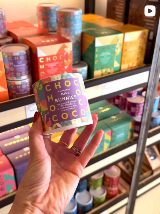 A hand holding a Chococo hot chocolate container in front of stocked shelves