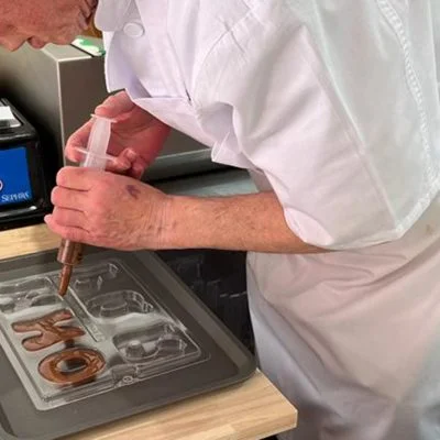 A chocolatier piping into chocolate moulds