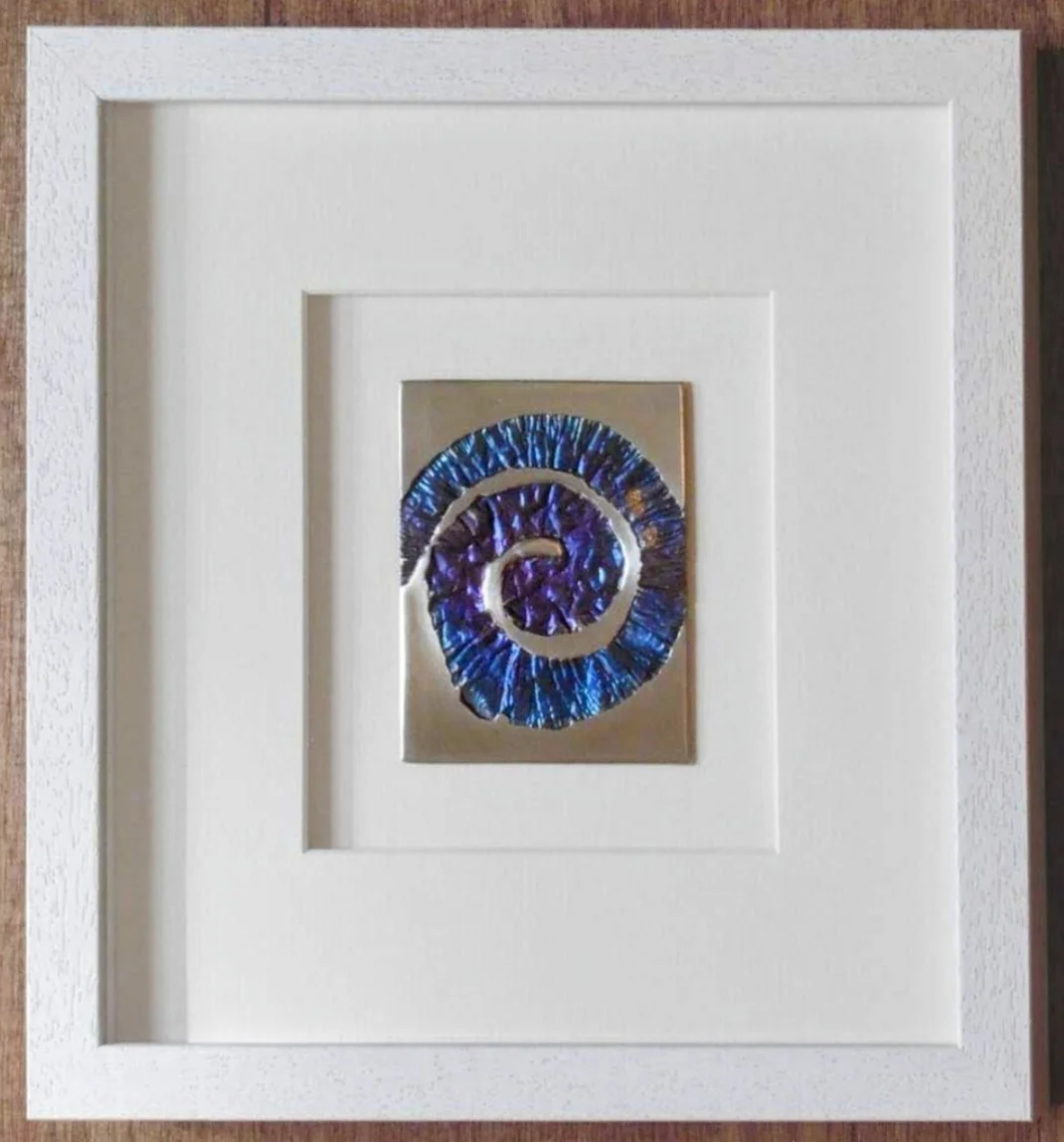 Blue spiral metal artwork in a white frame