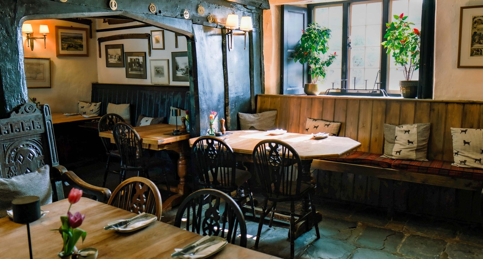 Characterful dining room with stone floor, wooden tables and framed pictures