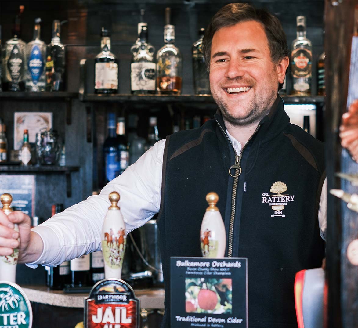 A member of The Church House Inn team pouring a drink behind the bar