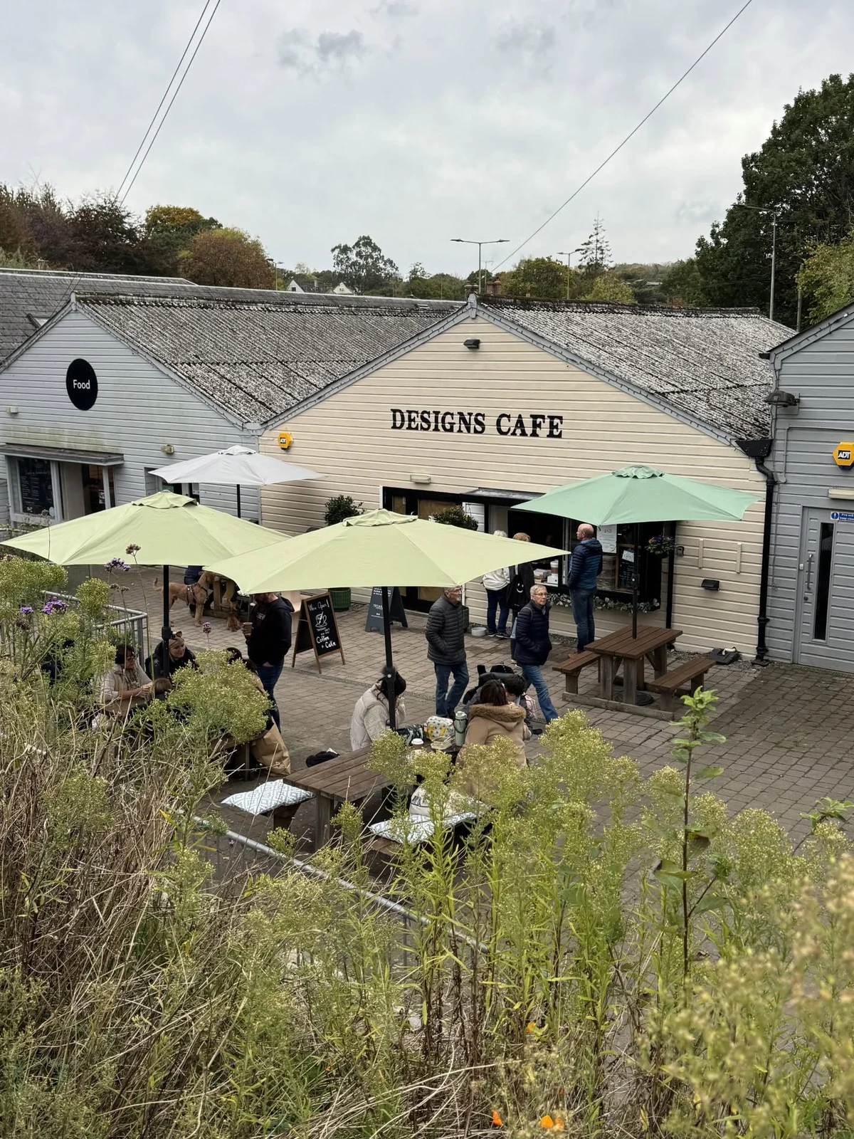 Designs Café with green parasols and outdoor seating at the Cider Press Centre