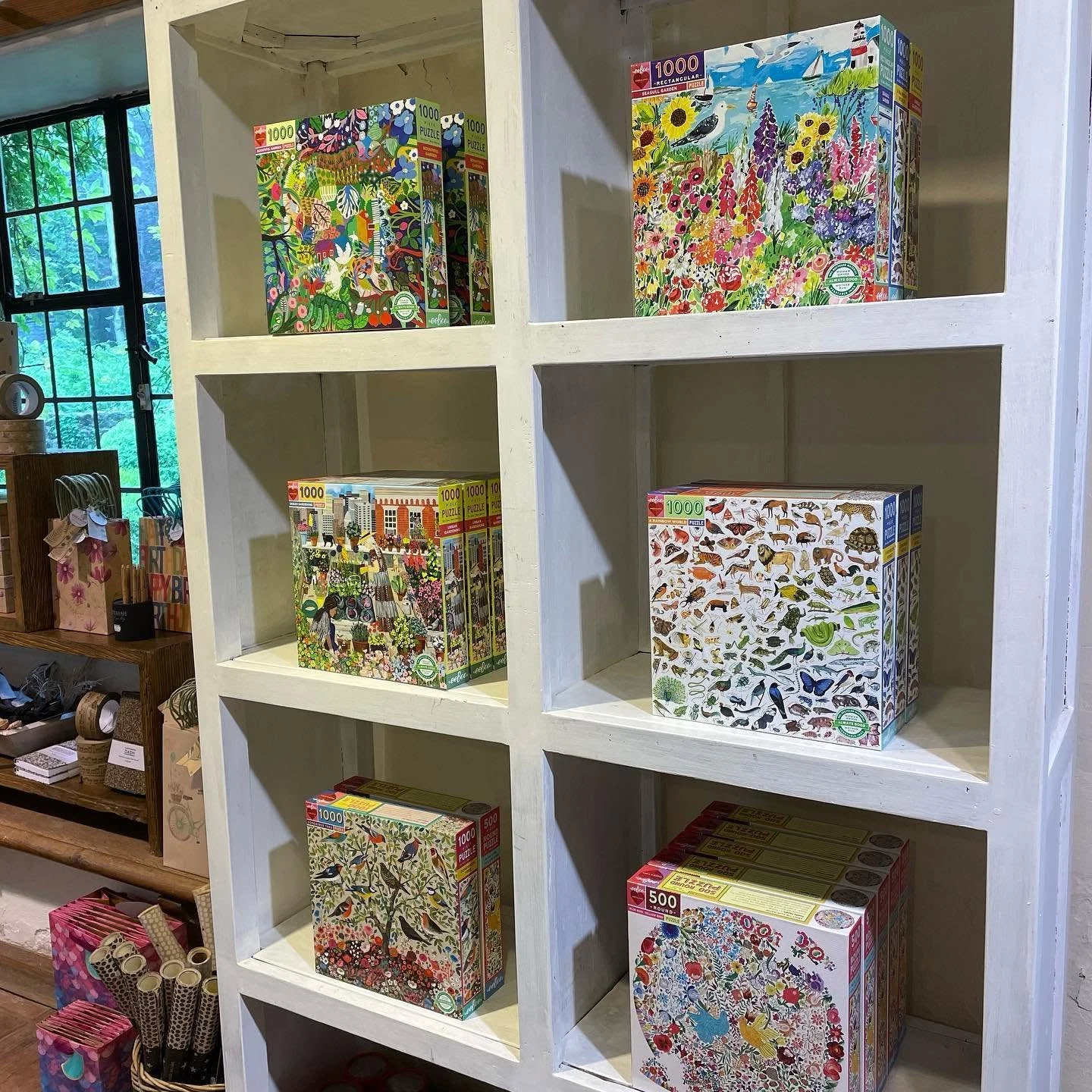 Colourful illustrated jigsaw puzzles displayed on white shop shelves