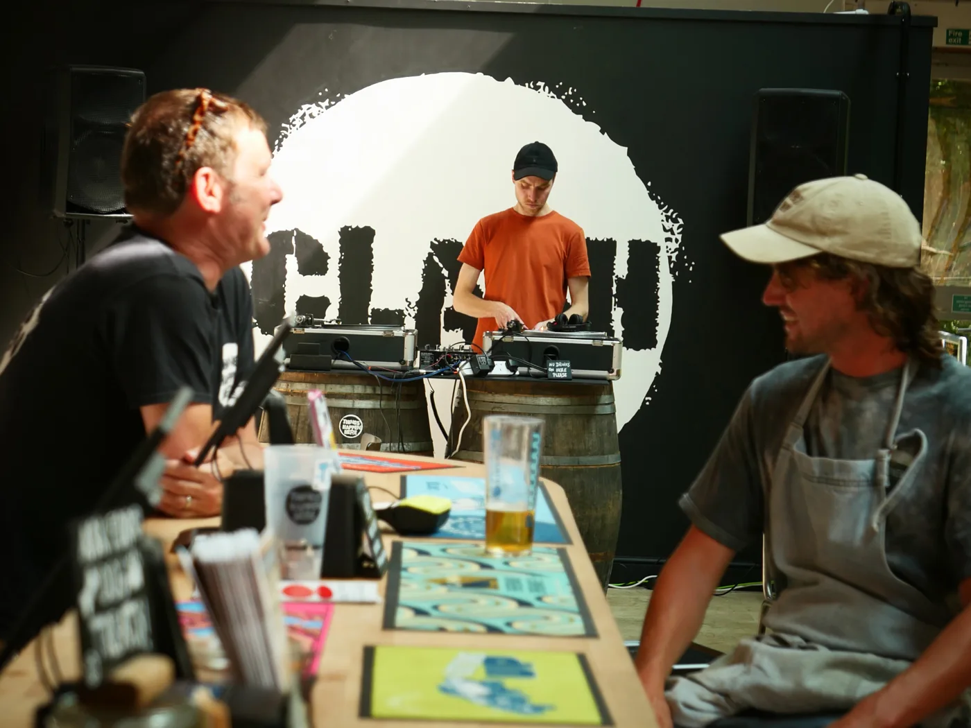 A DJ playing behind guests at the CLASH bar