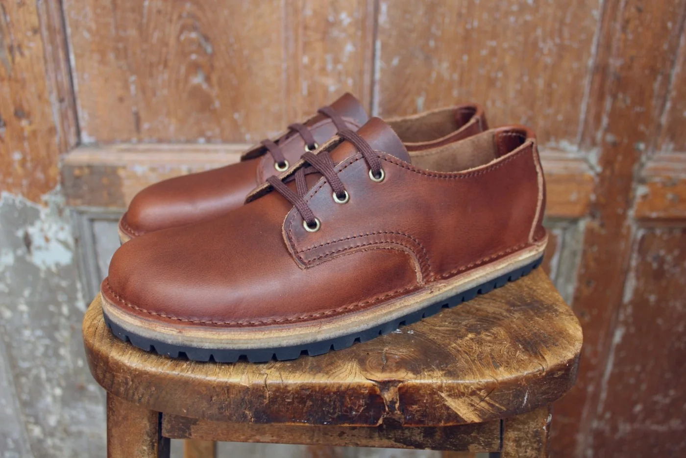 Mahogany leather Conker shoes resting on a worn wooden chair