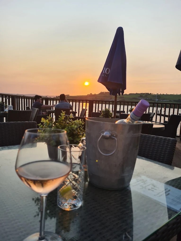 A glass of rosé and a wine cooler on the terrace at sunset, overlooking the Teign estuary