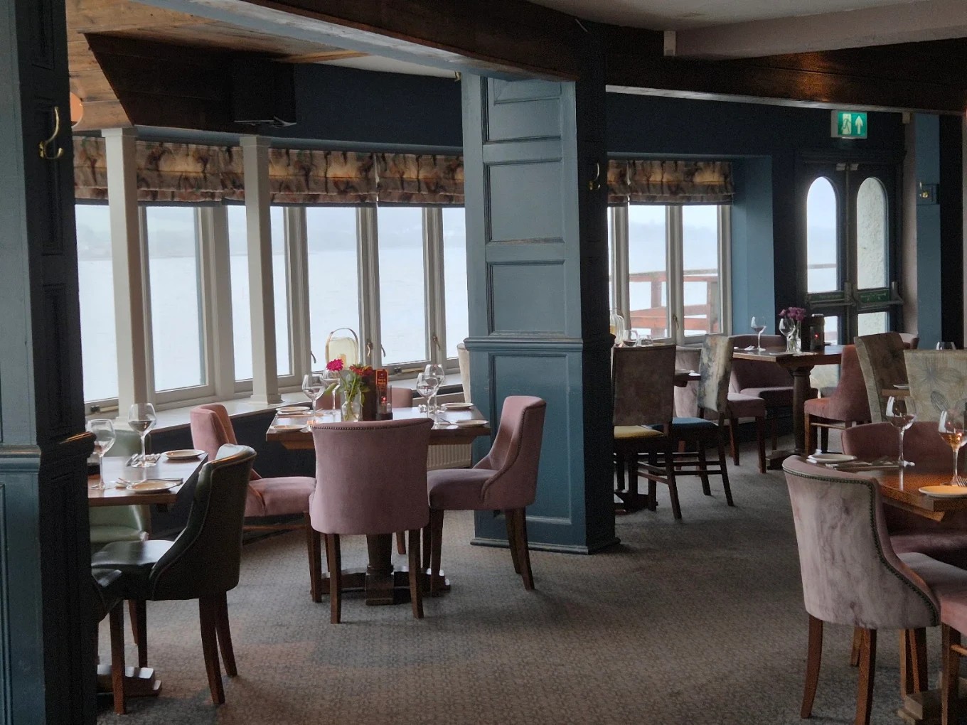 Pink upholstered dining chairs beside large windows overlooking the estuary
