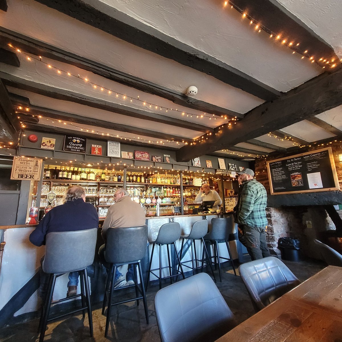 Timber-beamed bar with stools, framed pictures and strings of lights