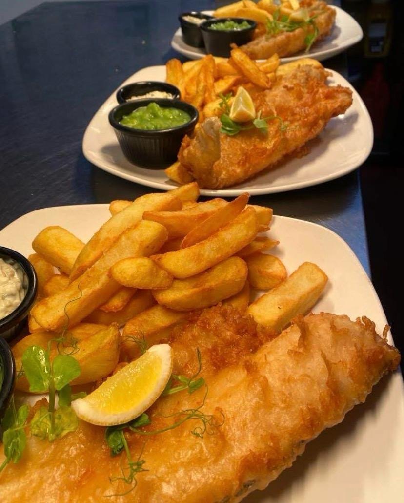 Beer-battered fish and thick-cut chips served with peas and lemon