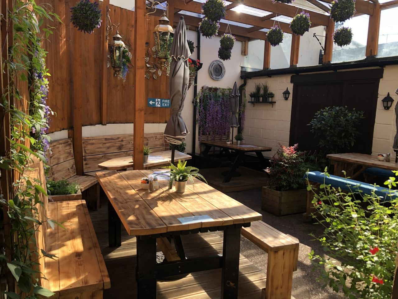 Timber tables surrounded by hanging plants in The Courtyard Sidmouth