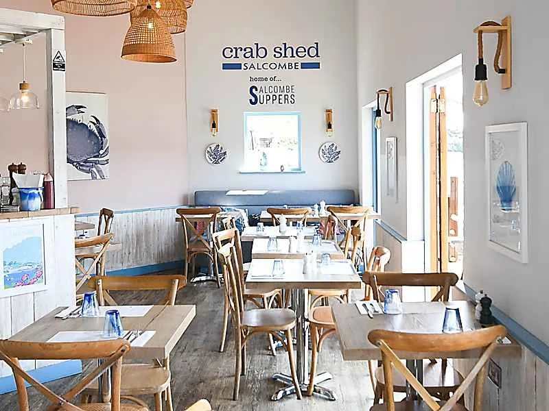 Bright dining room with wooden tables and coastal prints