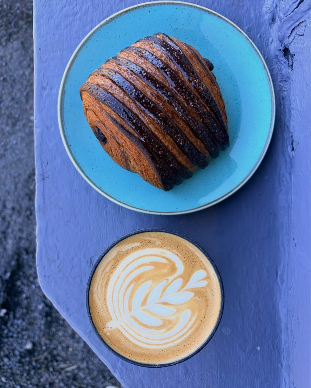 Coffee and a chocolate-striped pastry on a colourful outdoor table