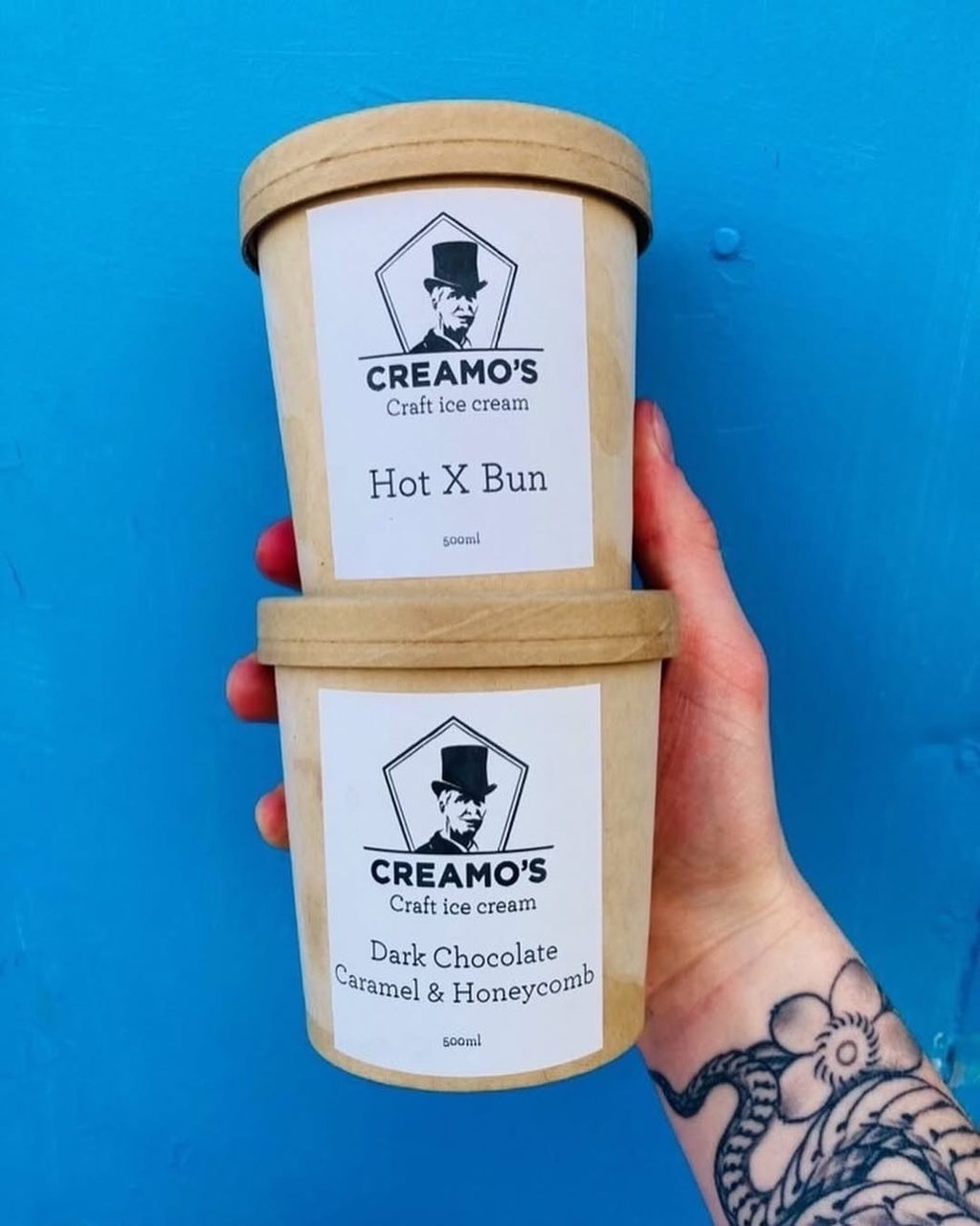 Two branded Creamo’s take-home ice cream tubs held against a blue background