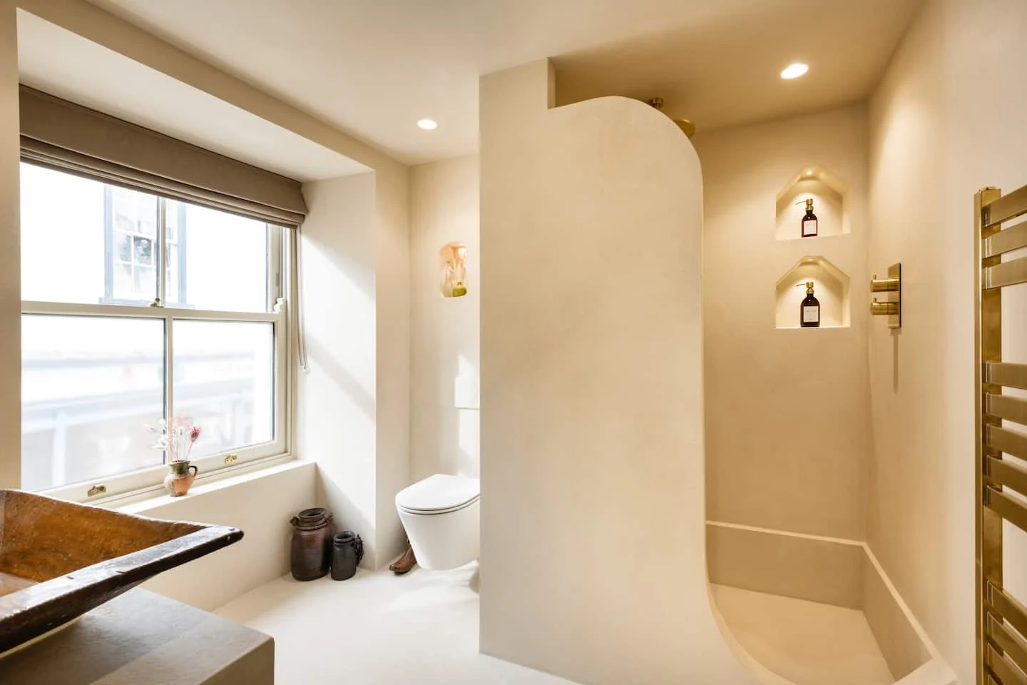 Curved walk-in shower and a window beside the bathroom basin
