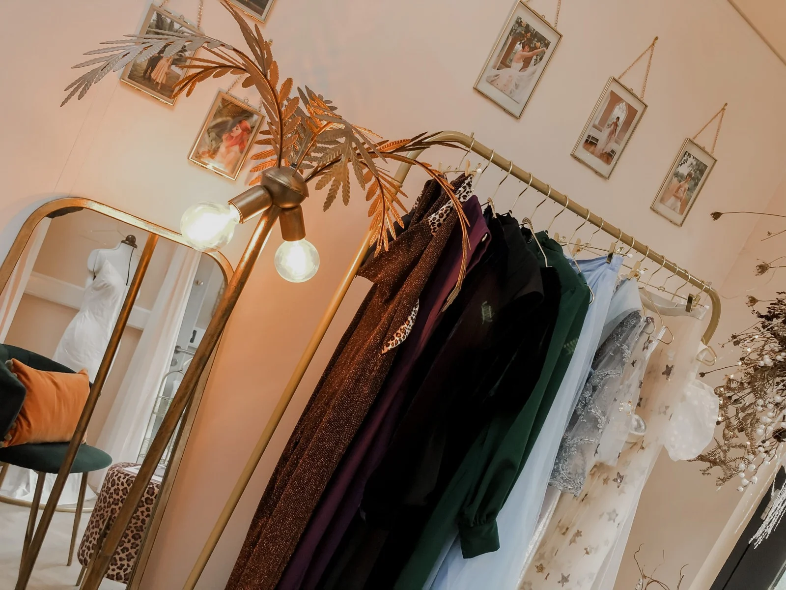 Rail of garments beside a gold-framed mirror