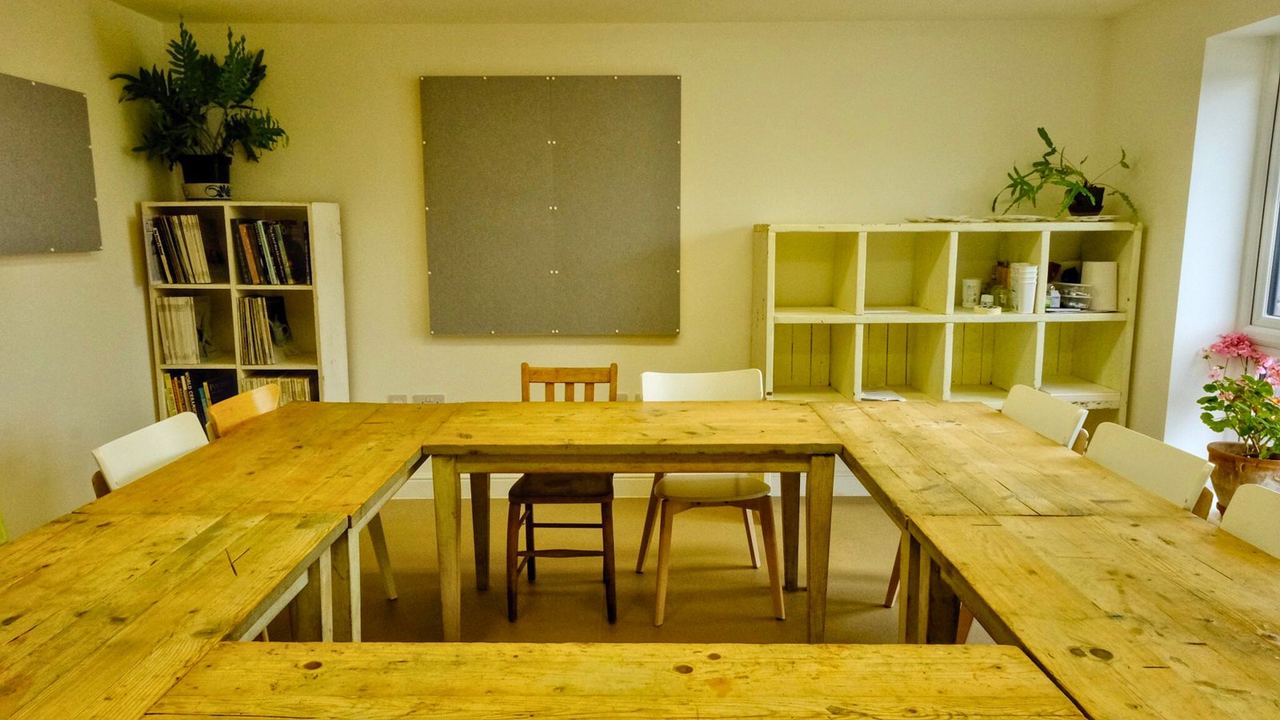 Long wooden tables in the light-filled community room