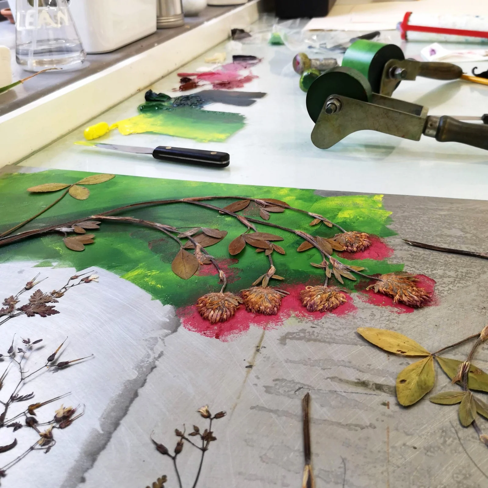 Botanical printmaking materials, ink rollers and colourful papers on a worktable