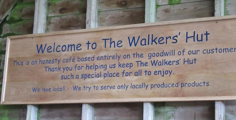 Wooden welcome sign explaining the Walkers’ Hut honesty café