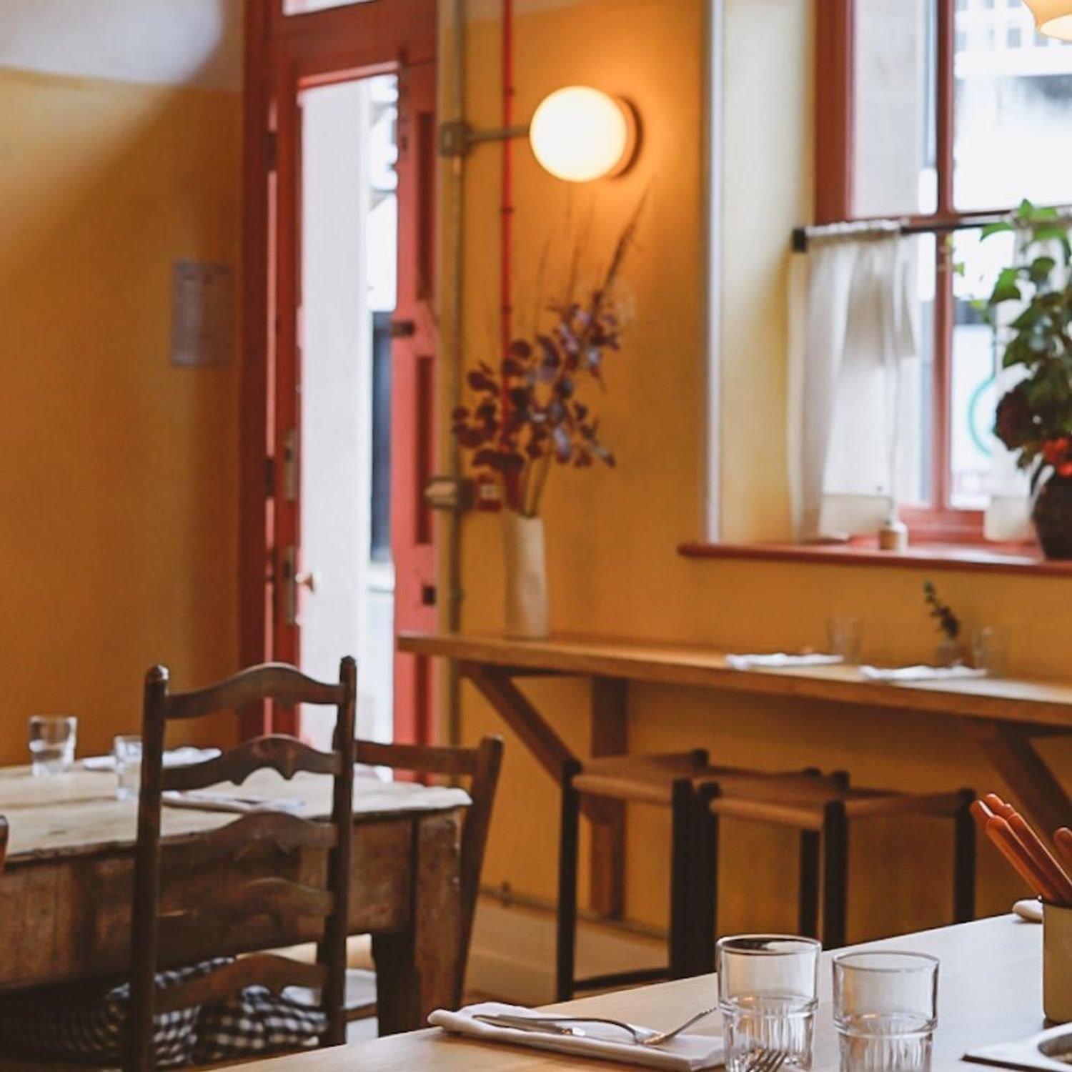 Warm orange walls and tables set for service inside Emilia in Ashburton