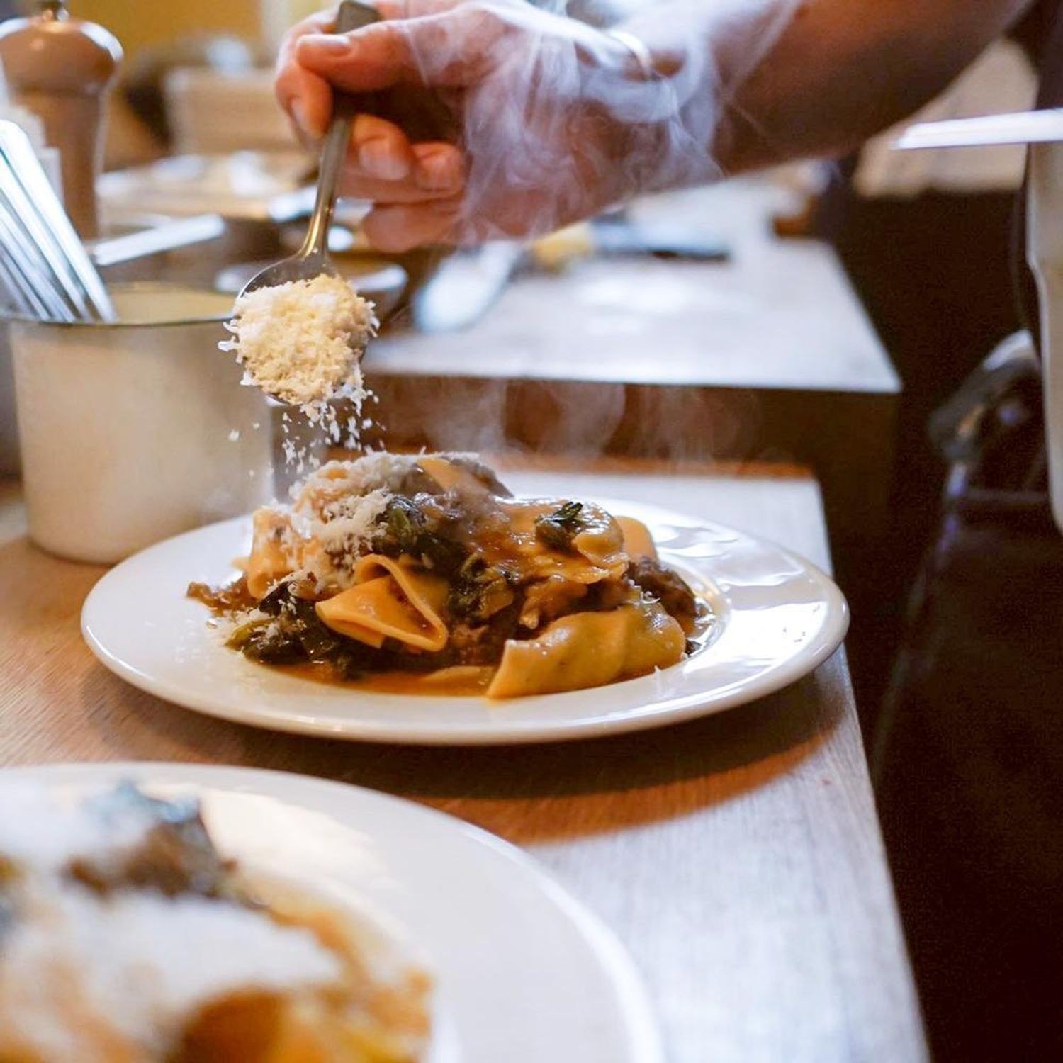 Freshly grated cheese falling onto a pasta dish at Emilia