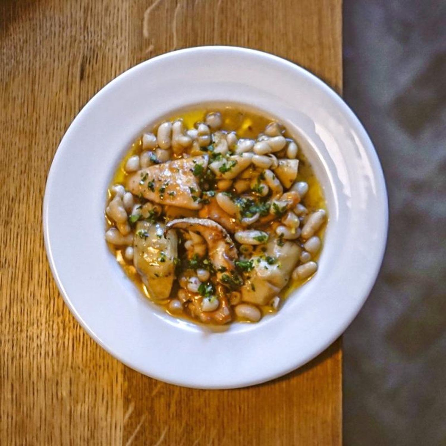 A seasonal dish with white beans on a plate at Emilia