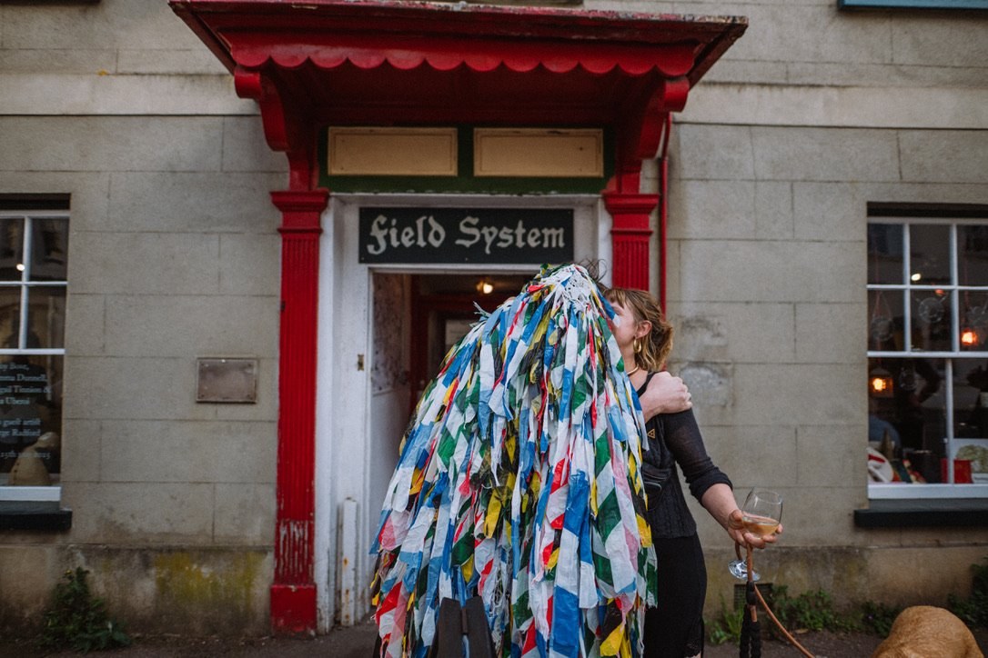 A colourful folk costume at the red doorway of Field System in Ashburton.