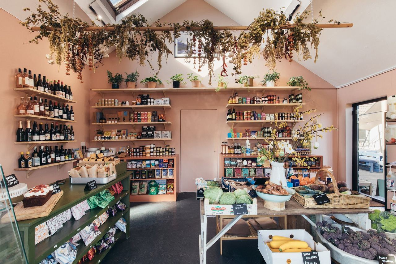 Pink-walled deli with hanging dried flowers and stocked shelves at Finns