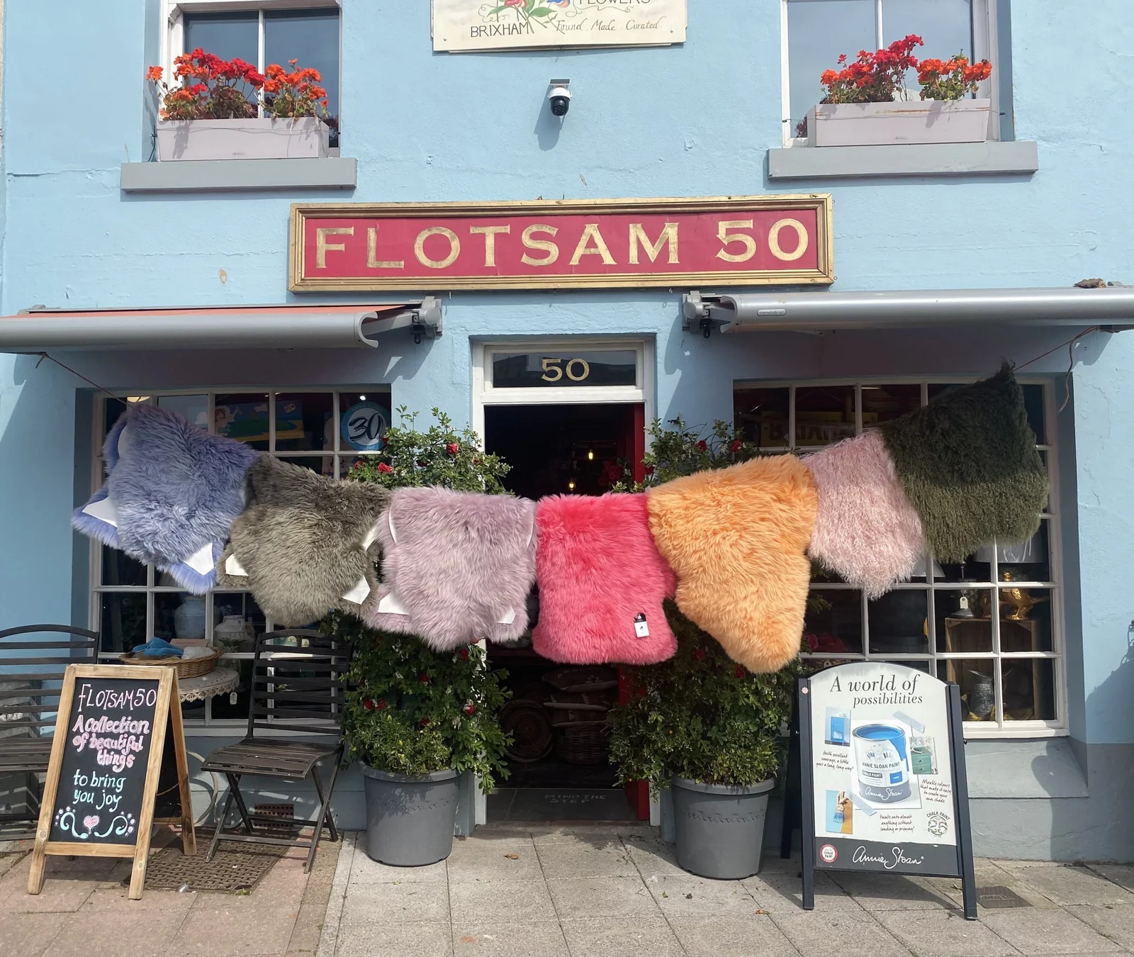 Blue-painted Flotsam 50 shopfront with colourful sheepskins outside