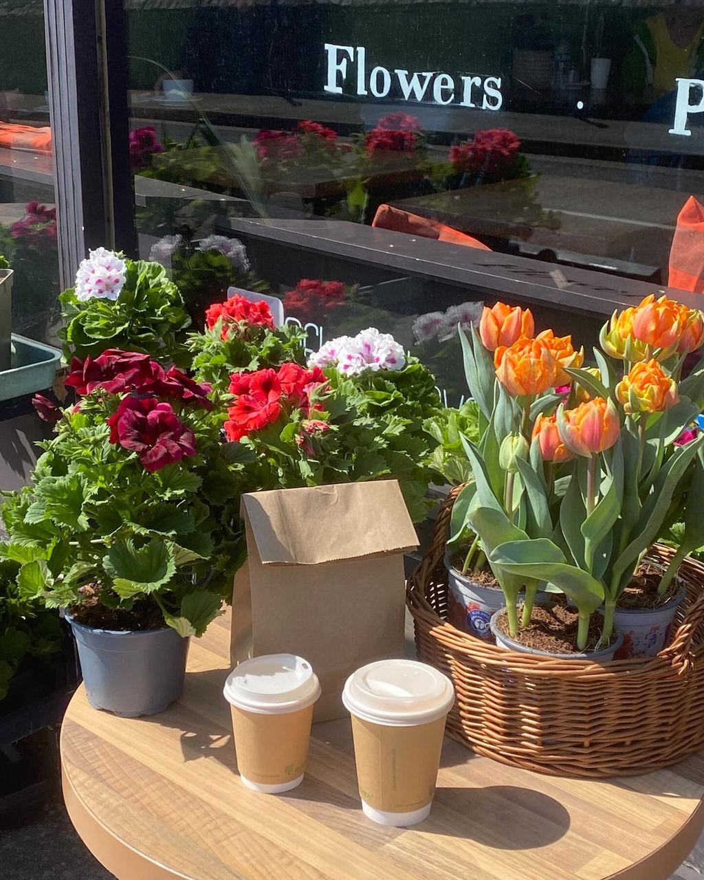Coffee cups beside flowers outside Flour Flower in Brixham