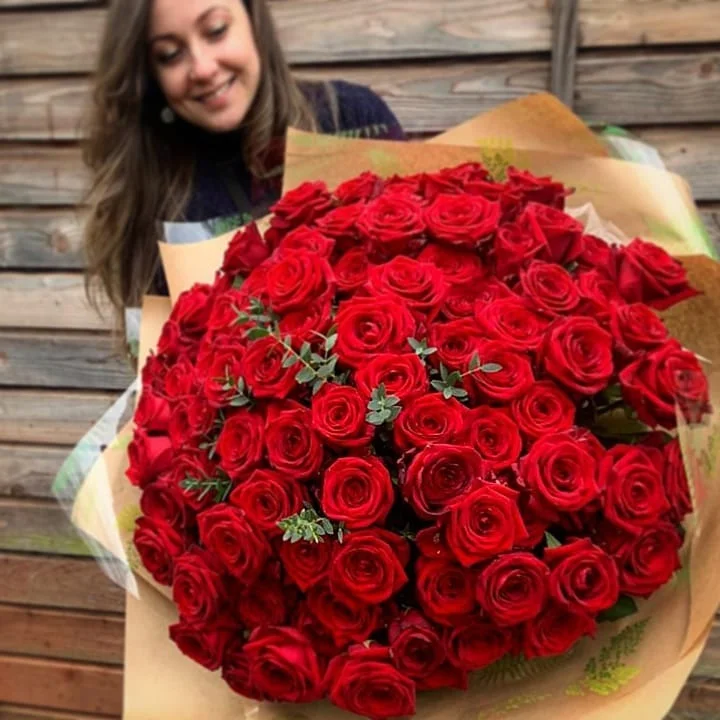 Vita holding a large bouquet of red roses