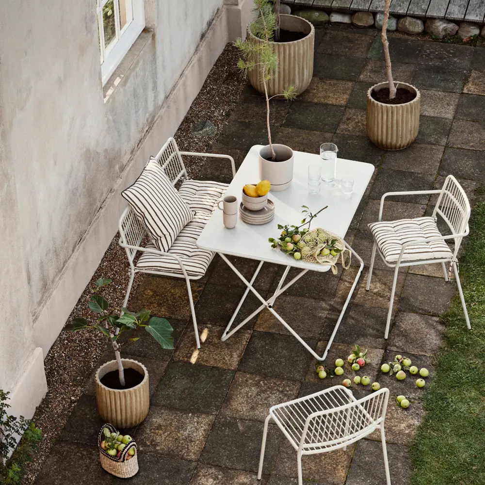 Outdoor table and white chairs in a Broste Copenhagen styling photograph