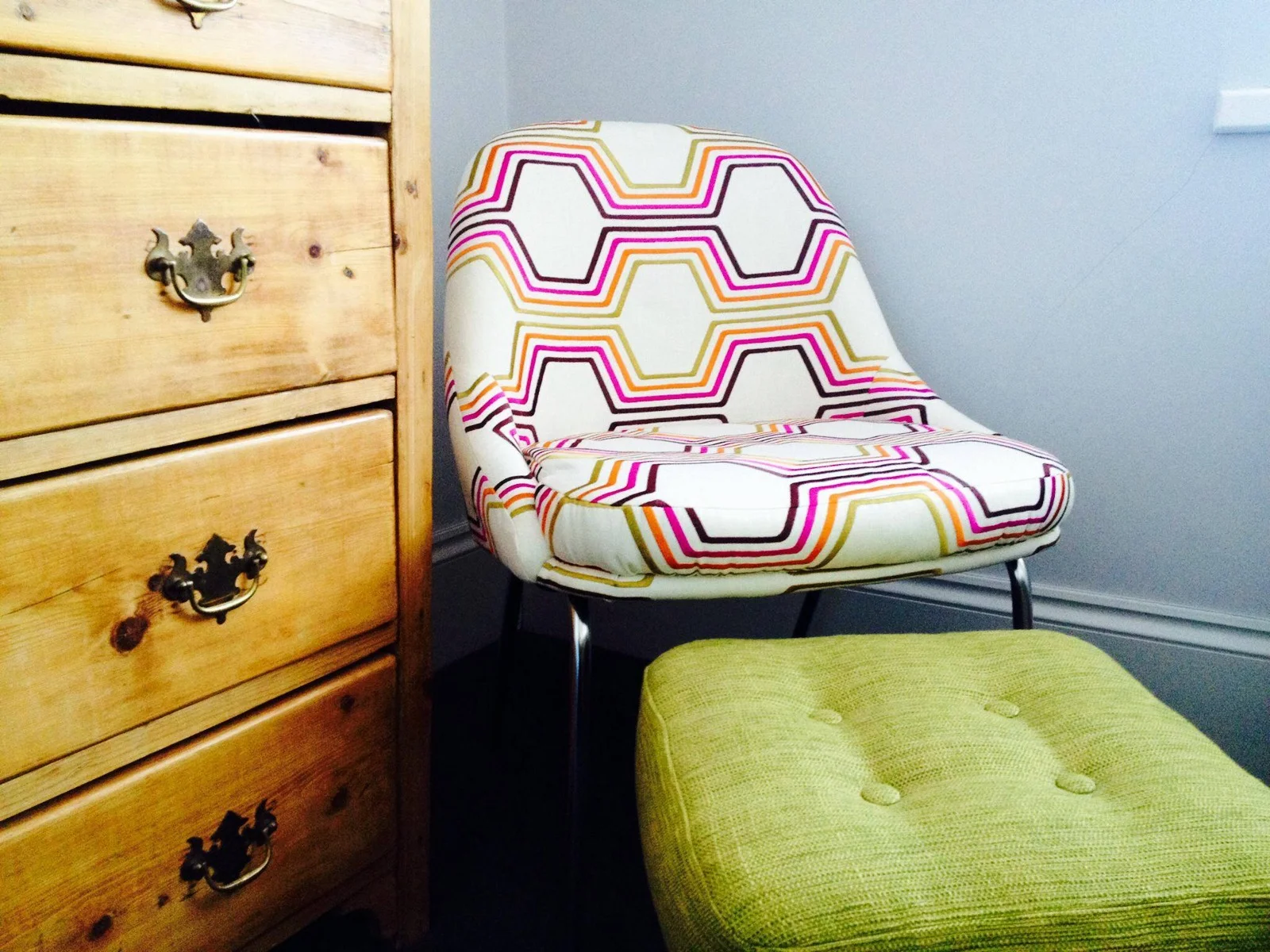 Patterned upholstered chair beside a chest of drawers