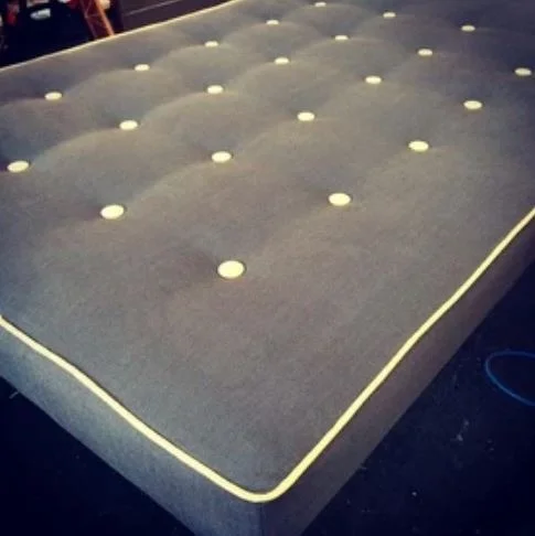 Dark upholstered cushion with deep buttoning and pale piping