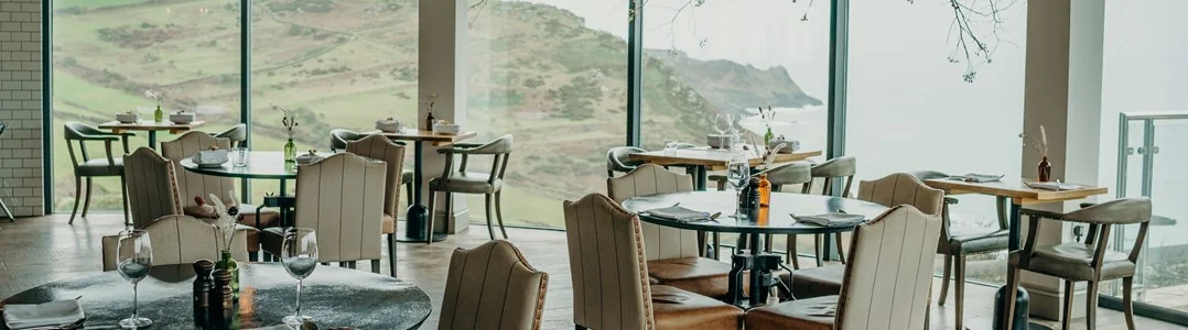 Sea-facing restaurant tables beside panoramic windows
