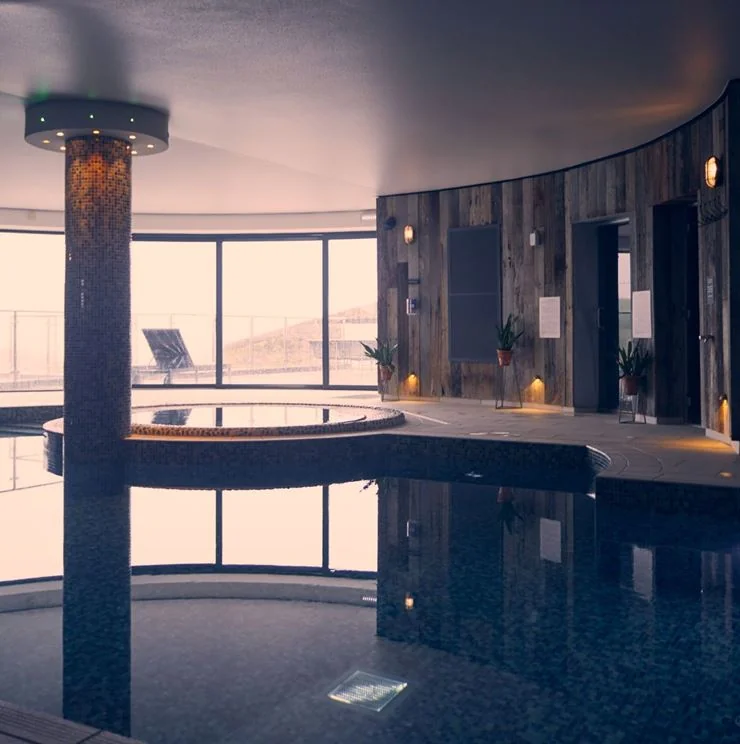 Indoor swimming pool beneath a curved ceiling with sea views
